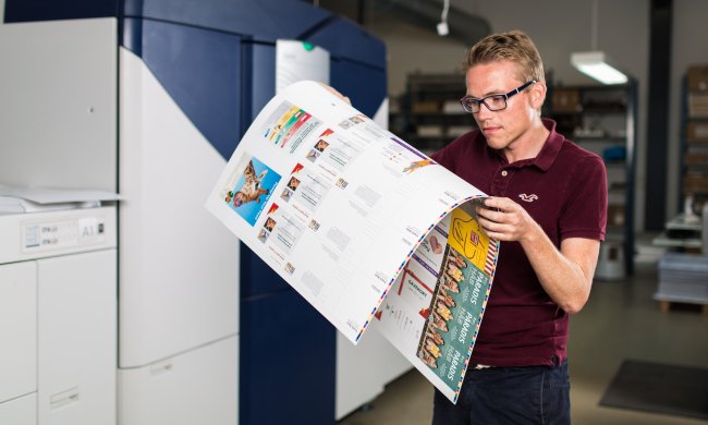 Man infront of Xerox Printer examining print