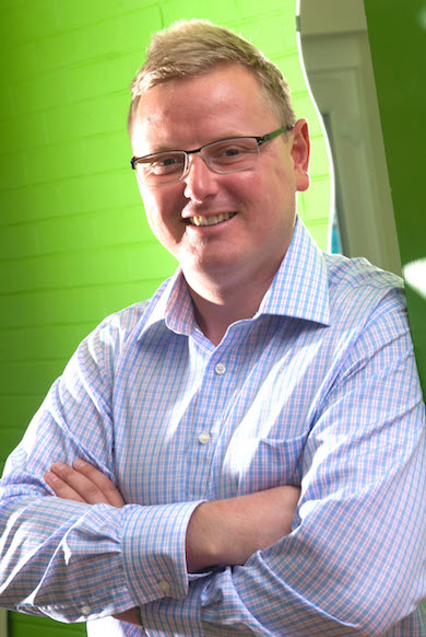 James Gray arms folded infront of green wall